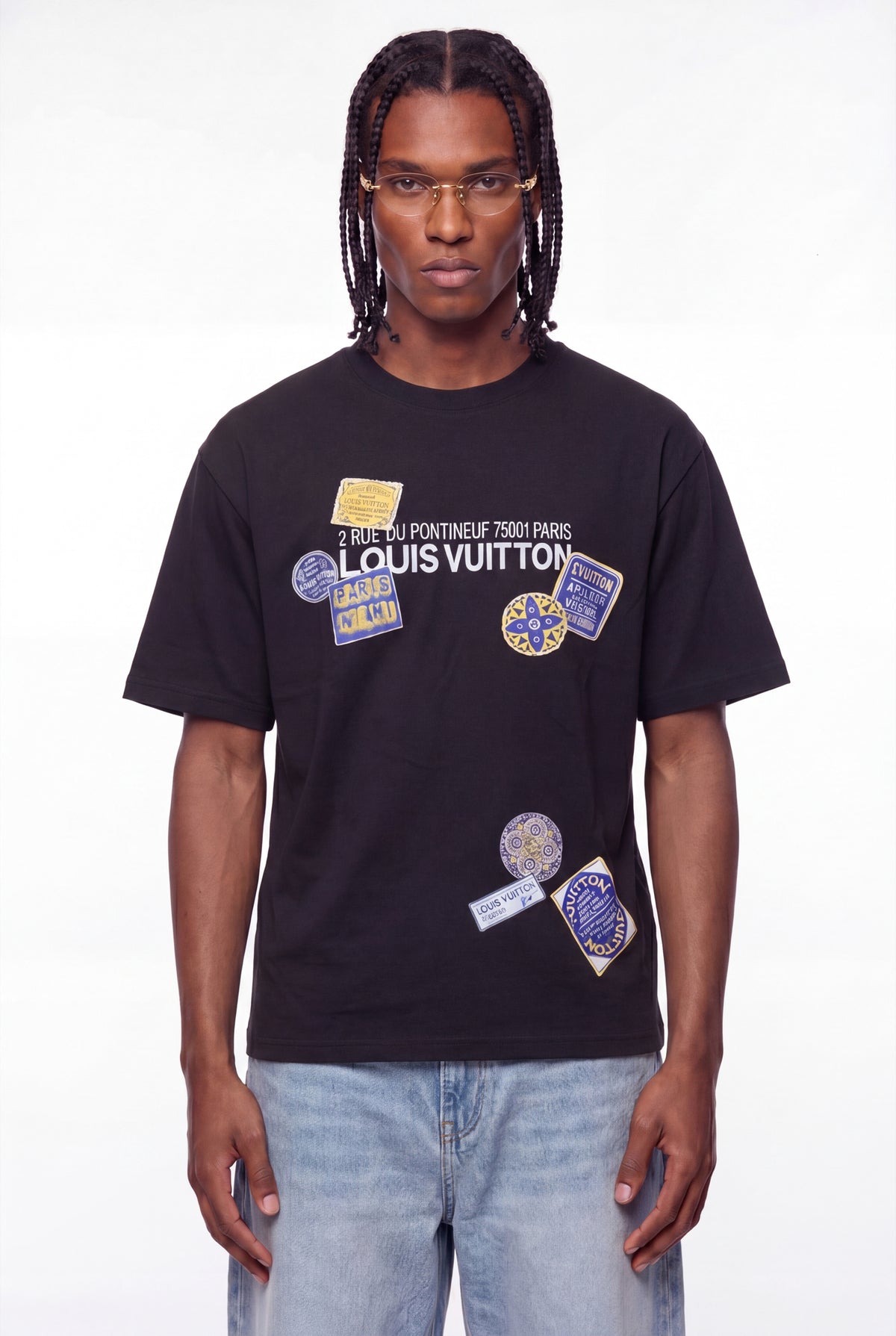 Person wearing a black Louis Vuitton t-shirt with various patches on a white background